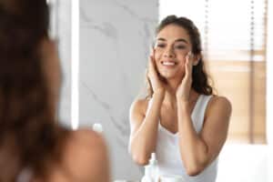 Woman looking in the mirror smiling after facelift in Dallas, TX