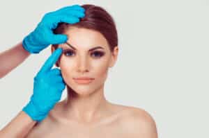 Beautiful woman with surgeon hands lifting her brow to prepare for a brow lift in Dallas
