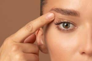 Close up of woman's eye as she touches eyelid wanting eyelid surgery in Dallas